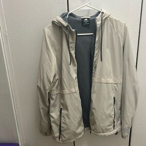 Beige New Balance raincoat w/ fleece lining. Size M. Small pen marking on back.